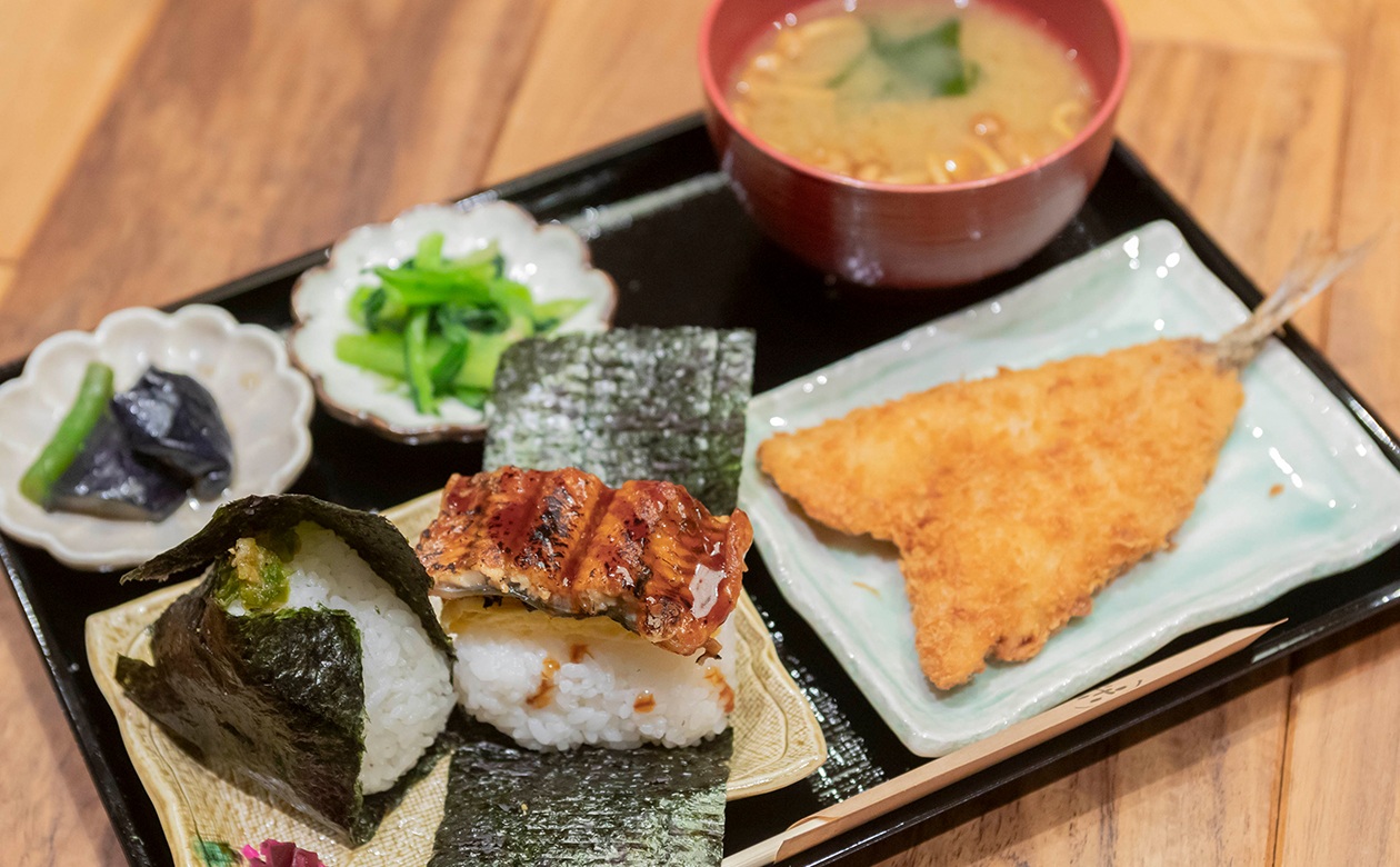 「日替わり定食」は好きなおむすび2個に、選べる日替わりのメイン料理1品、味噌汁とおばんざい2種、お漬物がセットで1,150円から。おむすびは西川選手が選んだ「うな玉」と「青唐辛子味噌」（319円）。味噌汁はプラス275円で「具沢山豚汁」に変更可。