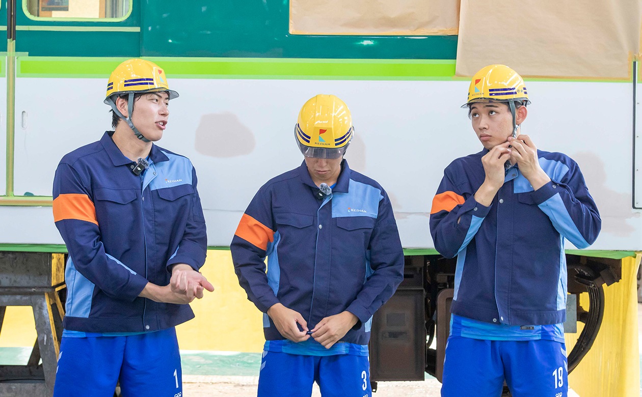 作業用の制服を借りて撮影の準備中。清水選手は肩幅ピッタリなものの、やはり袖の丈が短かった模様。