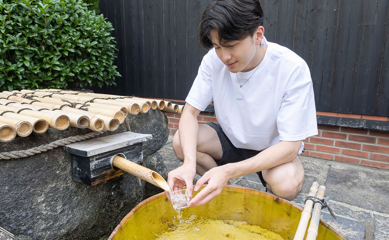 井戸からくみ上げた地下水を枡に注ぐ金田選手。はたしてお味は!?